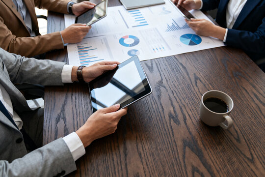 Business professionals analyzing data on tablets and documents during a meeting