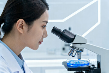 Female scientist examining sample under microscope in laboratory setting