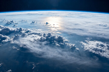 View of Earth's atmosphere and cloud cover from space, showcasing the curvature of the planet and sunlight reflecting off clouds