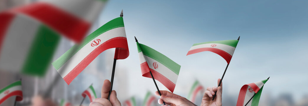 Iran flags in their hands on a blurred urban background