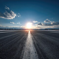 Asphalt road leading towards bright sunlight under a clear blue sky
