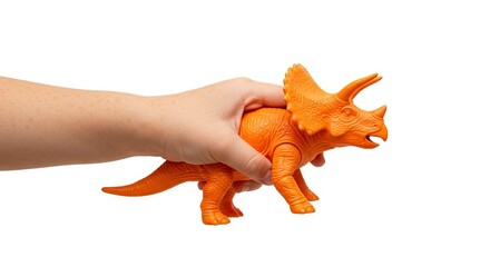 Naklejka premium A hand holds an orange plastic triceratops toy against a white background