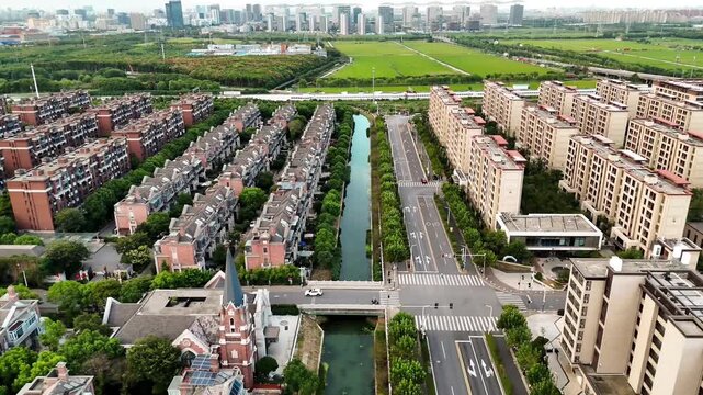 Drone sideways aerial video of modern residential city blocks with canal and road