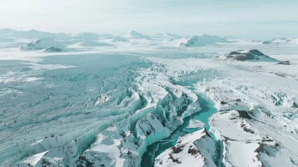 Aerial view of a glacier with turquoise meltwater streams flowing through snow-covered terrain