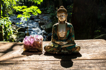 Meditating Buddha statue and amethyst in a serene natural setting in Brazil, symbolizing peace and spirituality.