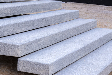 Close-up of modern granite staircase in an outdoor setting, juxtaposed with green vegetation. This...