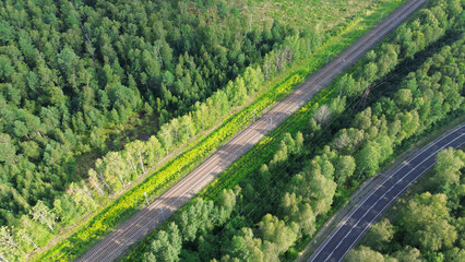 Railway and highway passing through forest captured from the sky