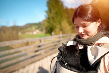 Woman hiking with black cat in backpack carrier