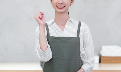 カフェでガッツポーズをするエプロンをつけた女性