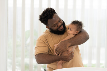 African American family. African American father carrying his newborn baby to bathe at home....