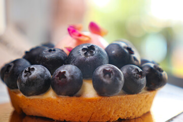 Fresh blueberry tart with delicate rose petals on top