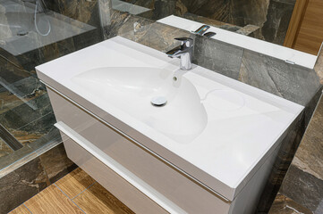 A modern bathroom vanity with a white sink, chrome faucet, and drawers. Marble and wood textures accent the space