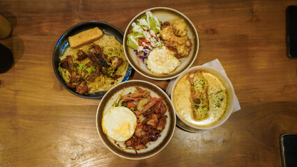 Assorted rice bowls and pasta dishes on a wooden table, top view