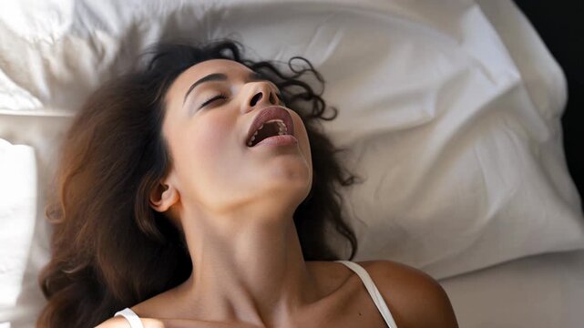 Female alone pleasures herself. Strong emotions and feelings, female feeling, satisfying, desire and loss of control. Young woman having orgasm in bed.