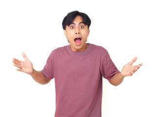 Shocked young Asian man with open mouth and raised hands showing surprised reaction on isolated...