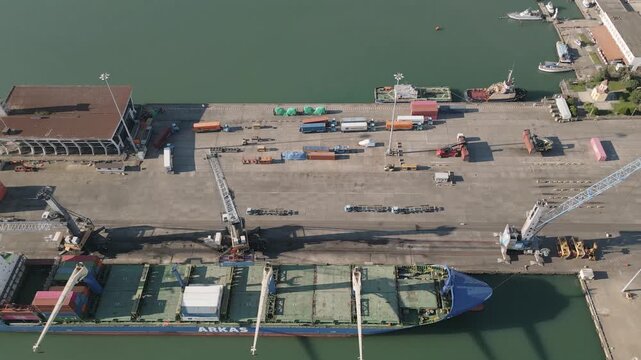 Poti, Georgia - 22nd august, 2025: Aerial top down view Cargo ship docked busy black sea seaport quay with cranes, containers, trucks, logistics operations, imports, exports, international trade hub