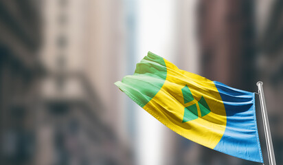 Saint Vincent and the Grenadines national flag waving on street. A beautiful with mast with blur buildings. Saint Vincent and the Grenadines national flag for independence day.