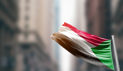Sudan national flag waving on street. A beautiful with mast with blur buildings. Sudan national...