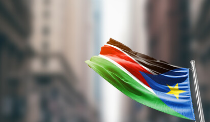 South Sudan national flag waving on street. A beautiful with mast with blur buildings. Sudan national flag for independence day.