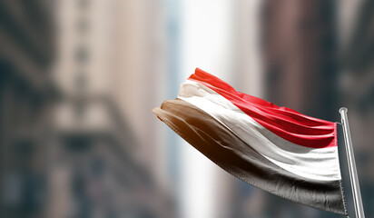 Yemen national flag waving on street. A beautiful with mast with blur buildings. Yemen national...