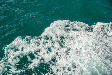 Aerial view of crashing foam waves. Dark teal ocean water with frothy white crests of waves breaking. Powerful ocean waves. Detailed view of ocean waves with white foam against deep blue water.