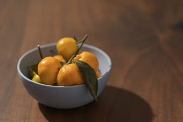 Fresh tangerines in a blue bowl on wood table