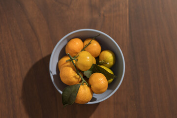 Fresh tangerines in a blue bowl on wood table