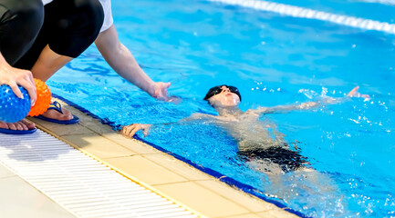 A boy in the pool to learn to swim or swim