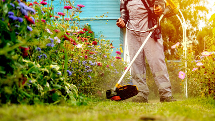A man mows the grass with a grass trimmer