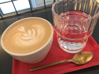 [Spain] A cup of latte and a glass and spoon of water placed on a red tray (Barcelona)