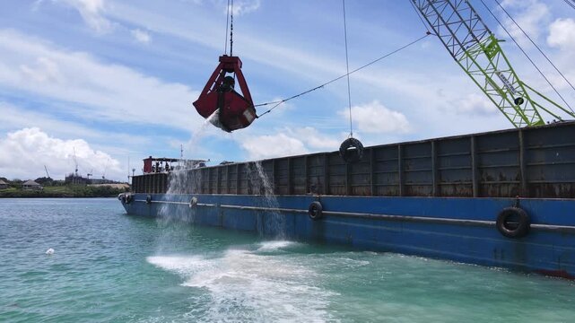 Marine dredging barge with crane excavating seabed soil