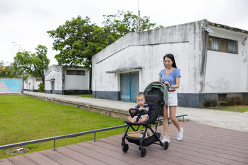 Mother walking with baby in stroller at park outdoors