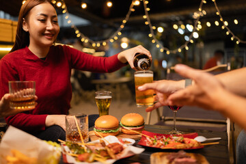 Happy Friends Celebrating Together at Night, Young Asian Group of Friends Having Fun and Toasting Drinks Outdoors, Enjoying a Celebration Concept.