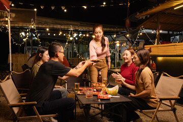 Happy Friends Celebrating Together at Night, Young Asian Group of Friends Having Fun and Toasting Drinks Outdoors, Enjoying a Celebration Concept.
