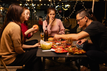 Happy Friends Celebrating Together at Night, Young Asian Group of Friends Having Fun and Toasting Drinks Outdoors, Enjoying a Celebration Concept.