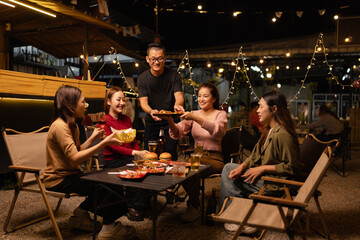 Happy Friends Celebrating Together at Night, Young Asian Group of Friends Having Fun and Toasting Drinks Outdoors, Enjoying a Celebration Concept.