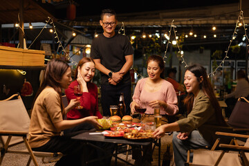 Happy Friends Celebrating Together at Night, Young Asian Group of Friends Having Fun and Toasting Drinks Outdoors, Enjoying a Celebration Concept.