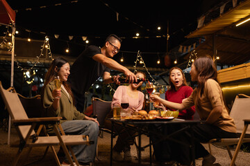 Happy Friends Celebrating Together at Night, Young Asian Group of Friends Having Fun and Toasting Drinks Outdoors, Enjoying a Celebration Concept.