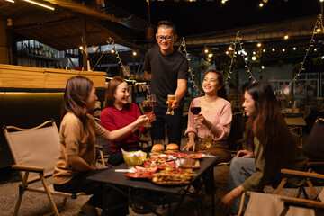 Happy Friends Celebrating Together at Night, Young Asian Group of Friends Having Fun and Toasting Drinks Outdoors, Enjoying a Celebration Concept.