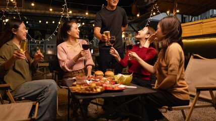 Happy Friends Celebrating Together at Night, Young Asian Group of Friends Having Fun and Toasting Drinks Outdoors, Enjoying a Celebration Concept.