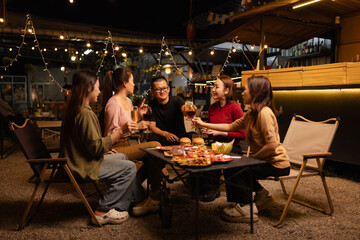 Happy Friends Celebrating Together at Night, Young Asian Group of Friends Having Fun and Toasting Drinks Outdoors, Enjoying a Celebration Concept.