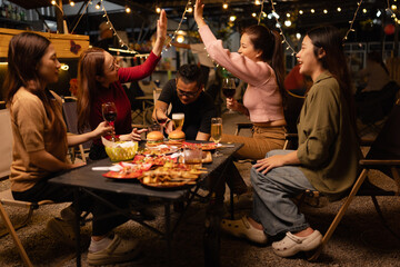 Happy Friends Celebrating Together at Night, Young Asian Group of Friends Having Fun and Toasting Drinks Outdoors, Enjoying a Celebration Concept.