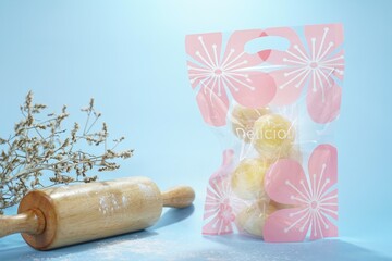 Golden mung bean cakes packed in a lovely floral bag. Soft, flaky, and sweet, they combine tradition with modern charm perfect as a gift or a delightful treat anytime. Industrial food. Free copy space