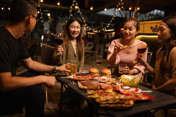 Happy Friends Celebrating Together at Night, Young Asian Group of Friends Having Fun and Toasting Drinks Outdoors, Enjoying a Celebration Concept.