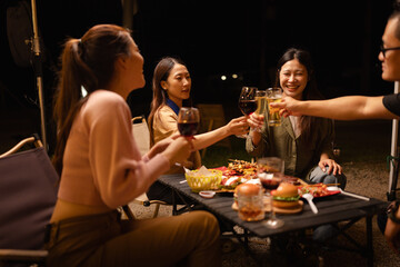 Happy Friends Celebrating Together at Night, Young Asian Group of Friends Having Fun and Toasting Drinks Outdoors, Enjoying a Celebration Concept.