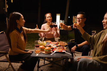 Happy Friends Celebrating Together at Night, Young Asian Group of Friends Having Fun and Toasting Drinks Outdoors, Enjoying a Celebration Concept.