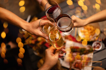 Concept for friendship, celebration, and lifestyle. A group of friends making a toast with various drinks wine, beer, and spirits during an outdoor night gathering. © SOMKID