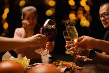Concept for friendship, celebration, and lifestyle. A group of friends making a toast with various drinks wine, beer, and spirits during an outdoor night gathering.