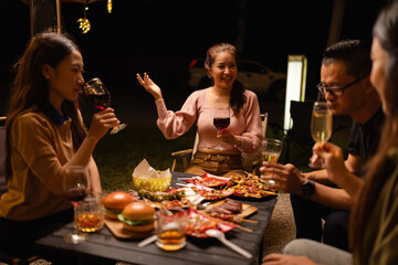 Happy Friends Celebrating Together at Night, Young Asian Group of Friends Having Fun and Toasting Drinks Outdoors, Enjoying a Celebration Concept.