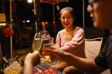 Happy Friends Celebrating Together at Night, Young Asian Group of Friends Having Fun and Toasting Drinks Outdoors, Enjoying a Celebration Concept.